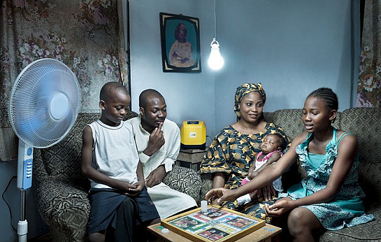 Eine afrikanische Familie freut sich über elektrisches Licht und einen Ventilator mit Strom aus Torfkraftwerken.